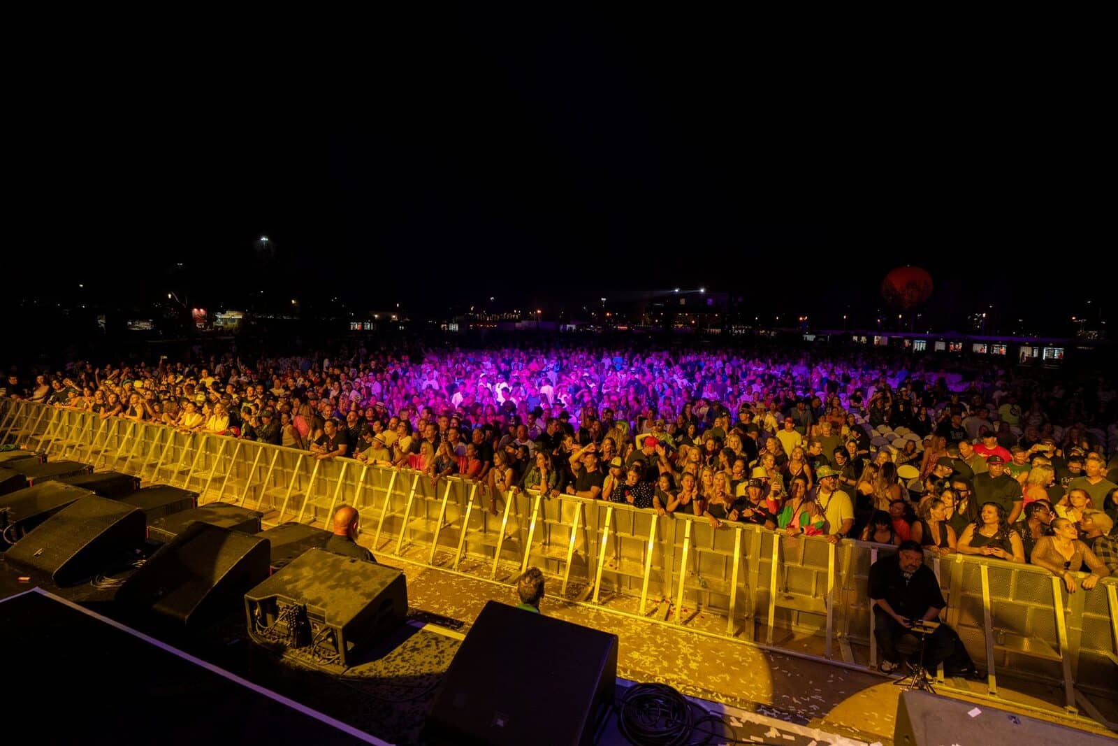 A night concert crowd under purple stage lights